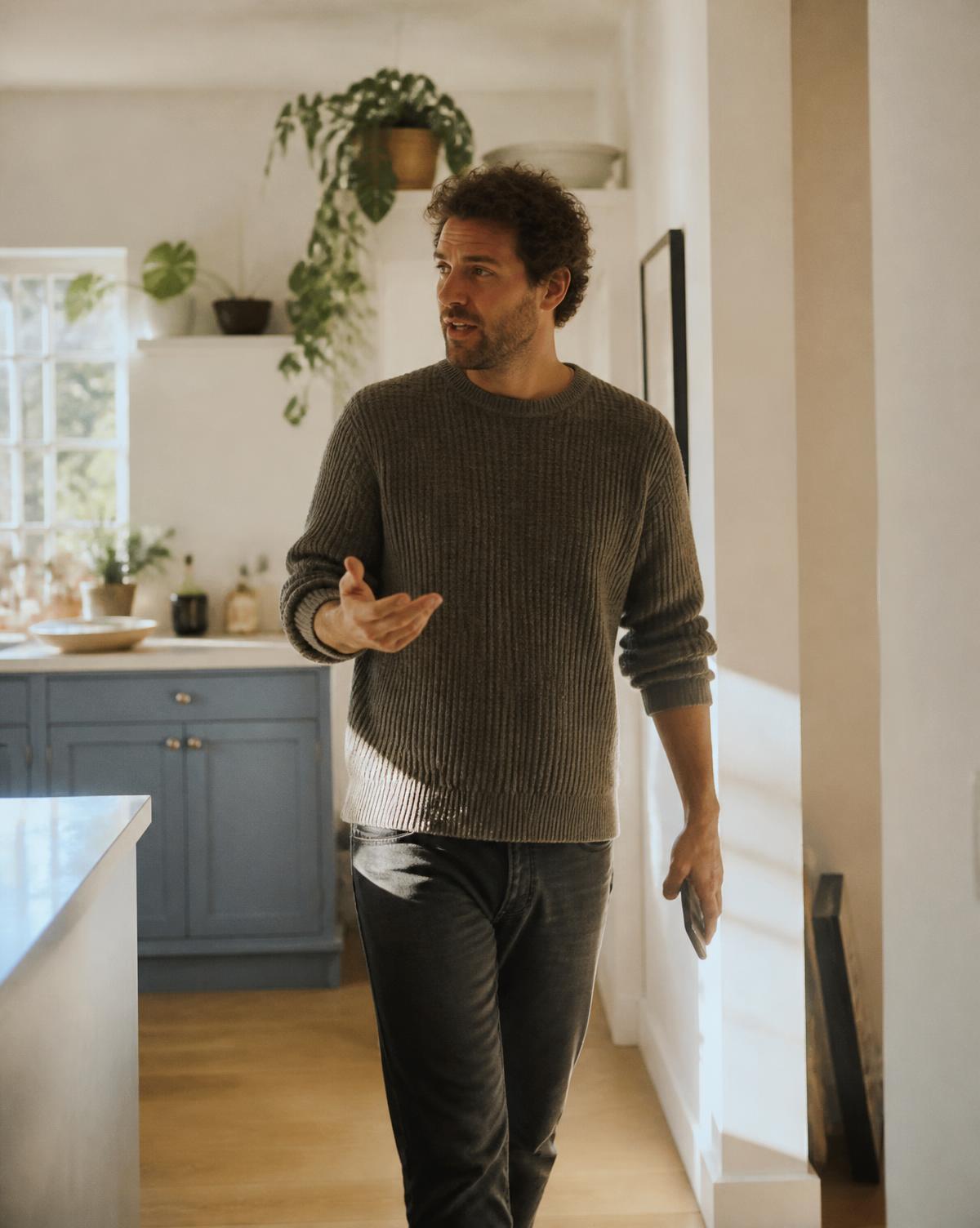 A man speaking as he walks through a sunlit kitchen